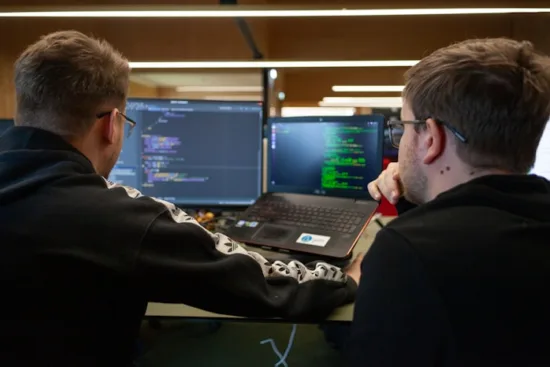 Two developers reviewing code on their monitors