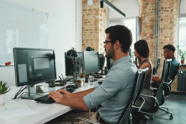 Colleagues working at desktop computers in a bright open-plan office